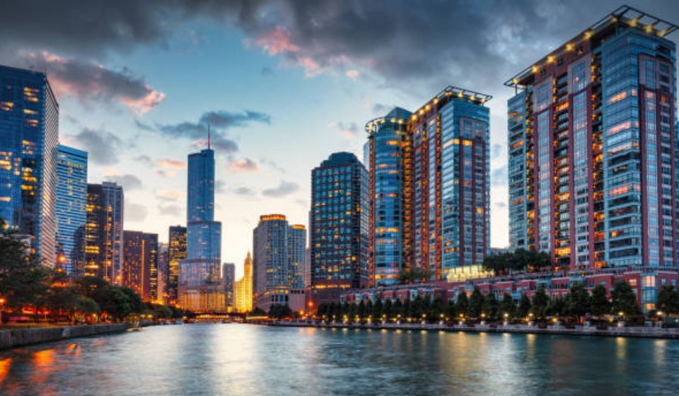 Chicago Urban Cityscape Sunset Twilight Panorama. Illuminated Chicago Urban Skyscrapers along the Chicago River. View from the Chicago River Waterfront at sunset twilight. Trump International Hotel and Tower in the background. Chicago, Illinois, USA, North America.